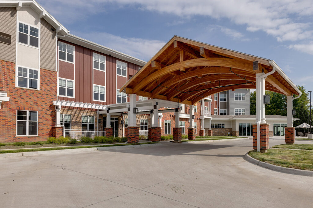 Covered entrance at Meadowview of Johnston senior living community in Johnston, Iowa, featuring the main building exterior and drive-up canopy.