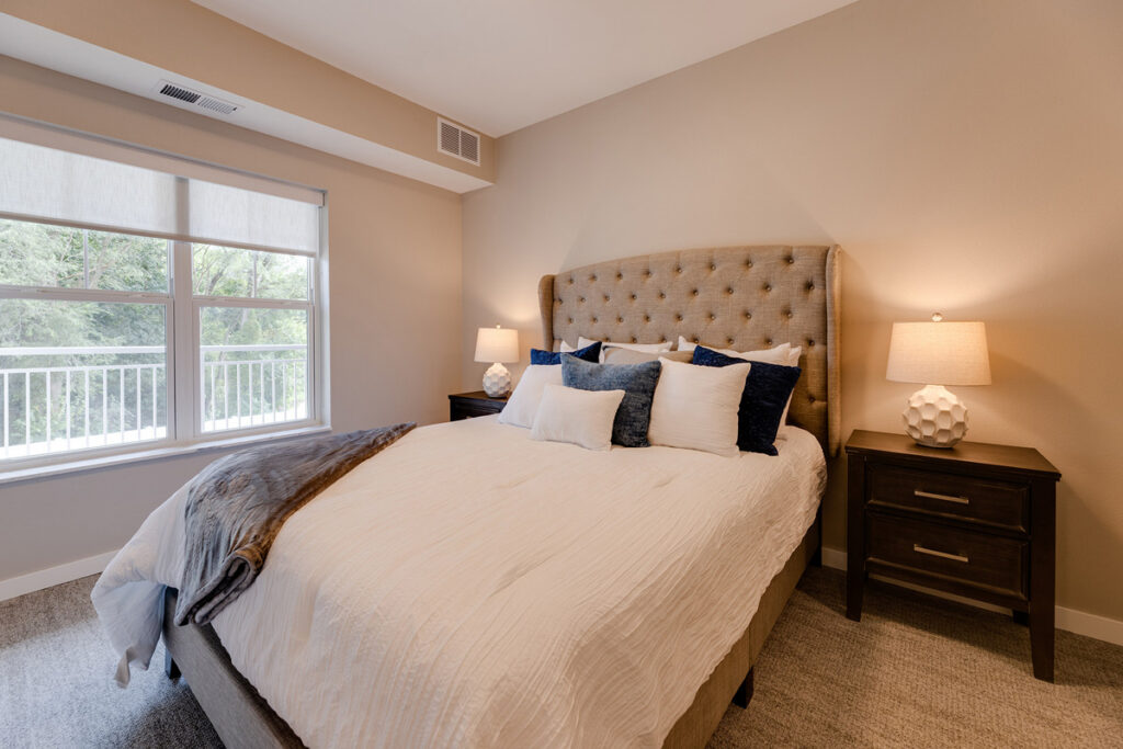 Apartment bedroom at Meadowview of Johnston featuring a spacious layout, large window, and comfortable furnishings.