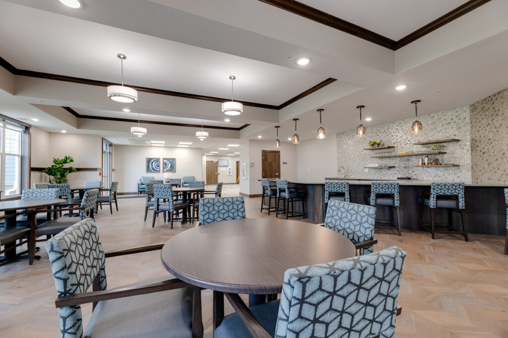 Bistro lounge at Meadowview of Johnston featuring flexible seating, café-style tables, and a beverage bar for resident gatherings.