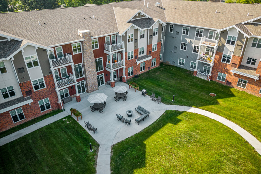Aerial view of the courtyard at Meadowview of Johnston senior living community featuring outdoor seating, walking paths, and landscaped green space.