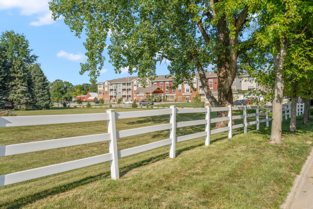Scenic view of Meadowview of Johnston senior living community in Johnston, Iowa, featuring landscaped grounds, mature trees, and the residential building.