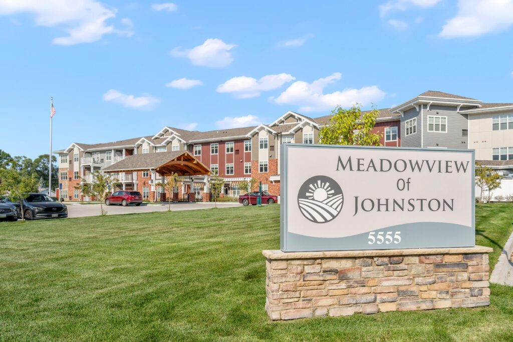 Exterior view of Meadowview of Johnston senior living community in Johnston, Iowa, featuring the community sign and main building entrance.