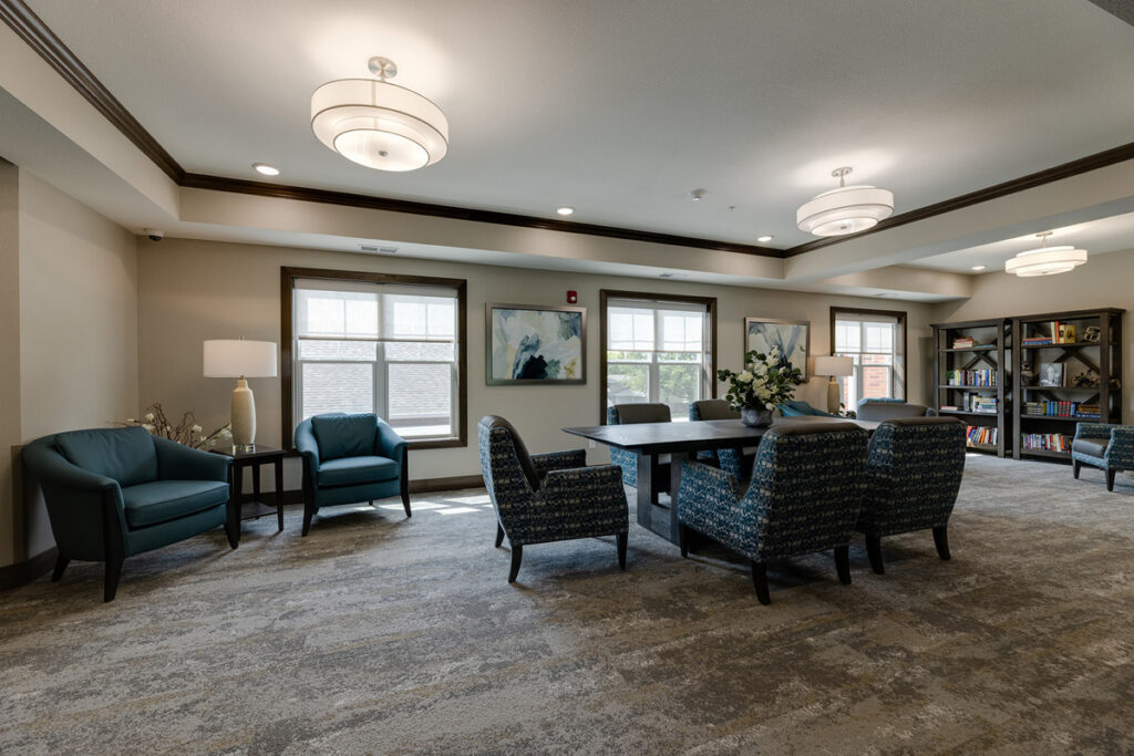 Library lounge at Meadowview of Johnston featuring comfortable seating, bookshelves, and a gathering space for reading, games, and social activities.