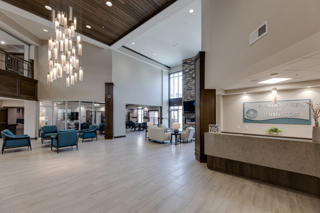 Welcoming lobby entrance at Meadowview of Johnston featuring the reception desk, fireplace, comfortable seating, and open gathering spaces.