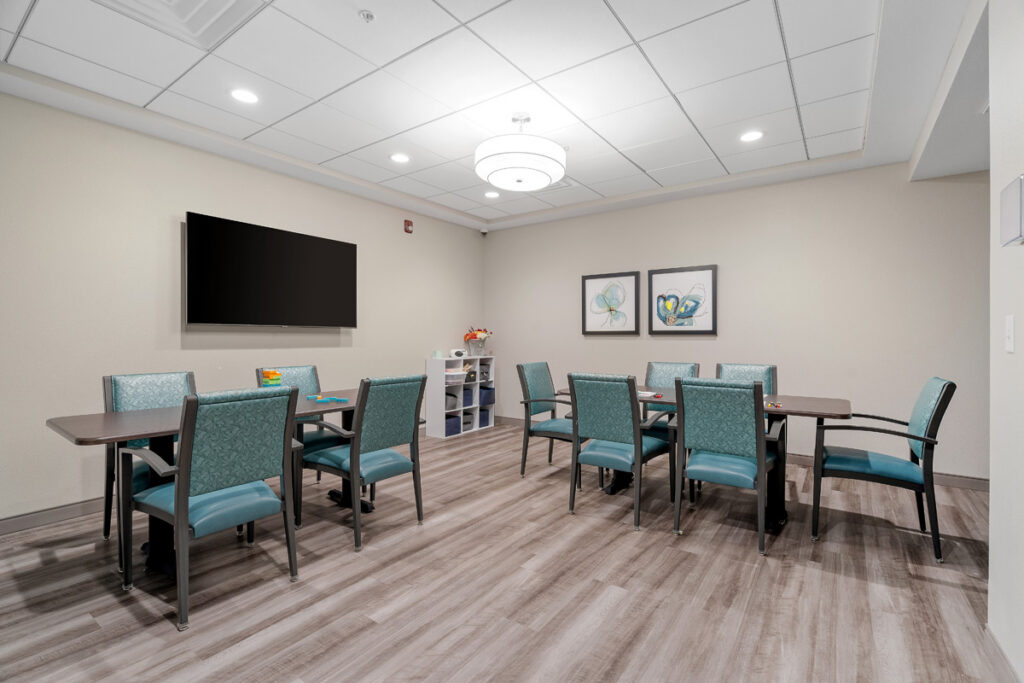Memory care activity room at Meadowview of Johnston featuring tables, seating, and dedicated space for engaging programs and small group activities.