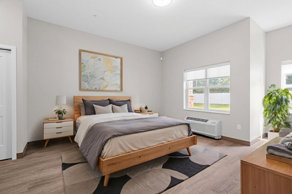 Memory care bedroom at Meadowview of Johnston featuring a spacious layout, large windows, comfortable furnishings, and a bright home-like environment.