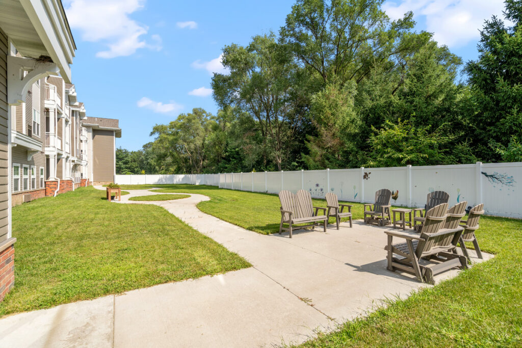 Secure memory care courtyard at Meadowview of Johnston featuring walking paths, outdoor seating, and landscaped green space for residents with memory loss.