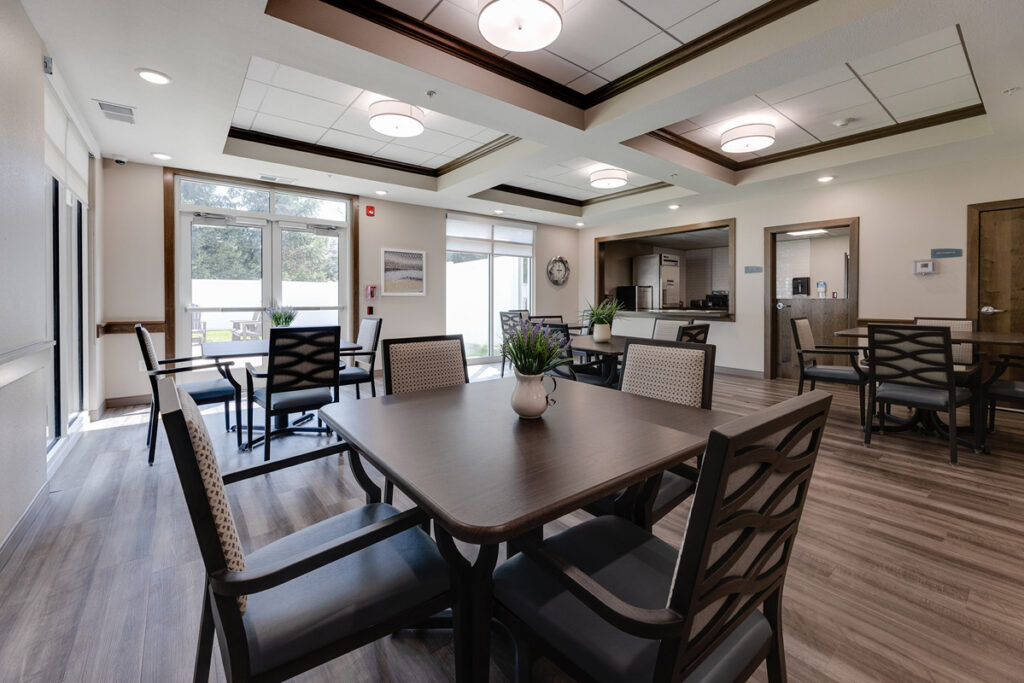 Memory care gathering space at Meadowview of Johnston featuring comfortable dining areas, natural light, and easy access to the secure outdoor courtyard.