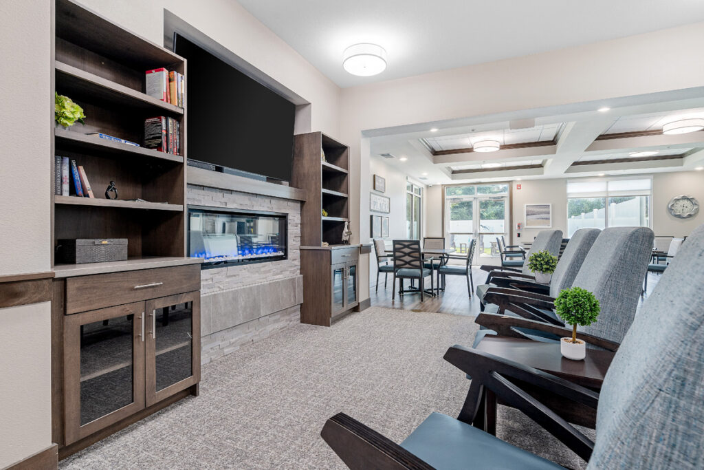 Memory care lounge at Meadowview of Johnston featuring comfortable seating, a fireplace, and welcoming common spaces designed for residents with memory loss.