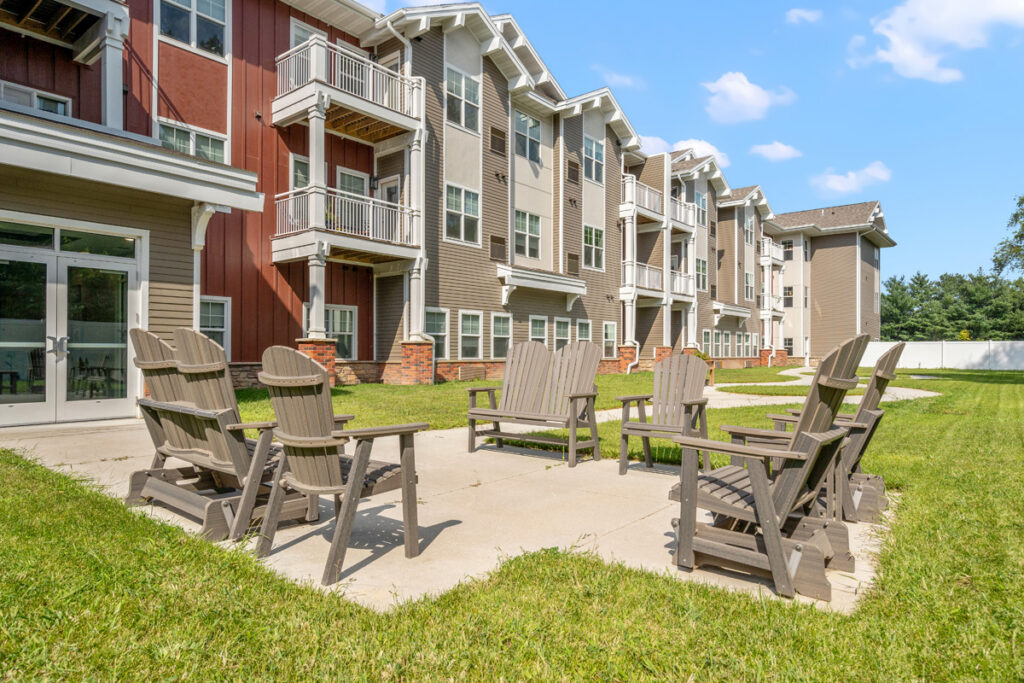 Outdoor patio in the secure memory care courtyard at Meadowview of Johnston featuring resident seating, walking paths, and access to the community building.
