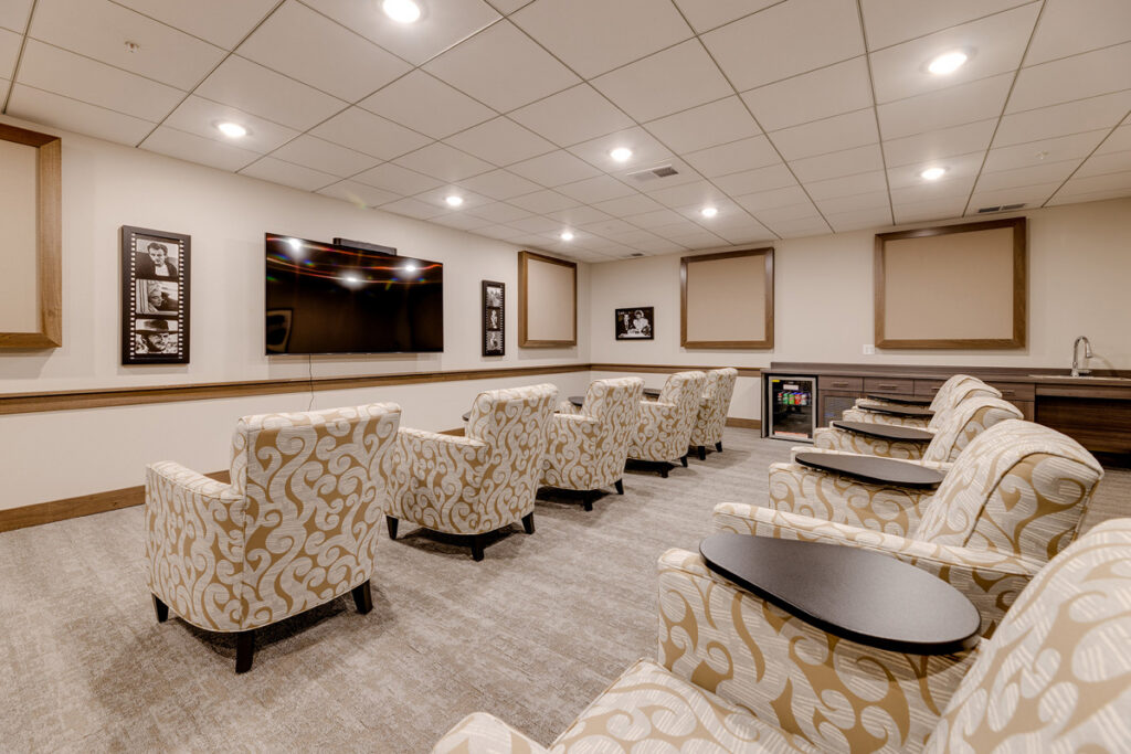 Movie lounge at Meadowview of Johnston featuring theater-style seating, a large screen, and space for resident entertainment and community events.