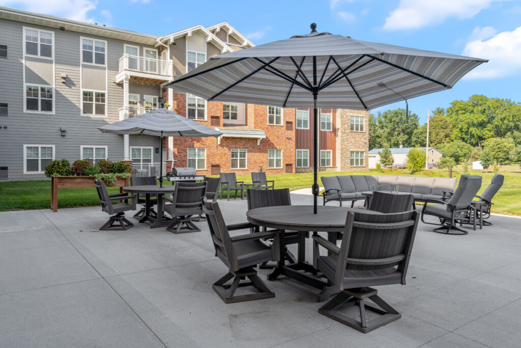 Outdoor patio seating area at Meadowview of Johnston senior living community featuring tables, umbrellas, and resident gathering space.