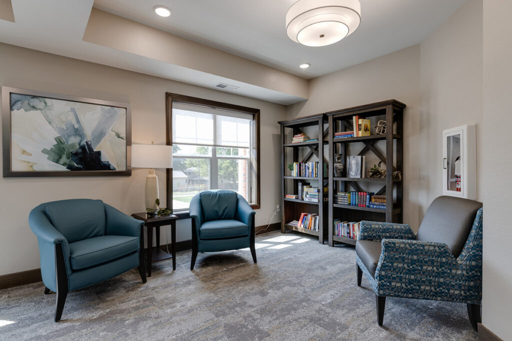 Quiet reading nook at Meadowview of Johnston featuring comfortable seating, bookshelves, and natural light for relaxation and leisure.