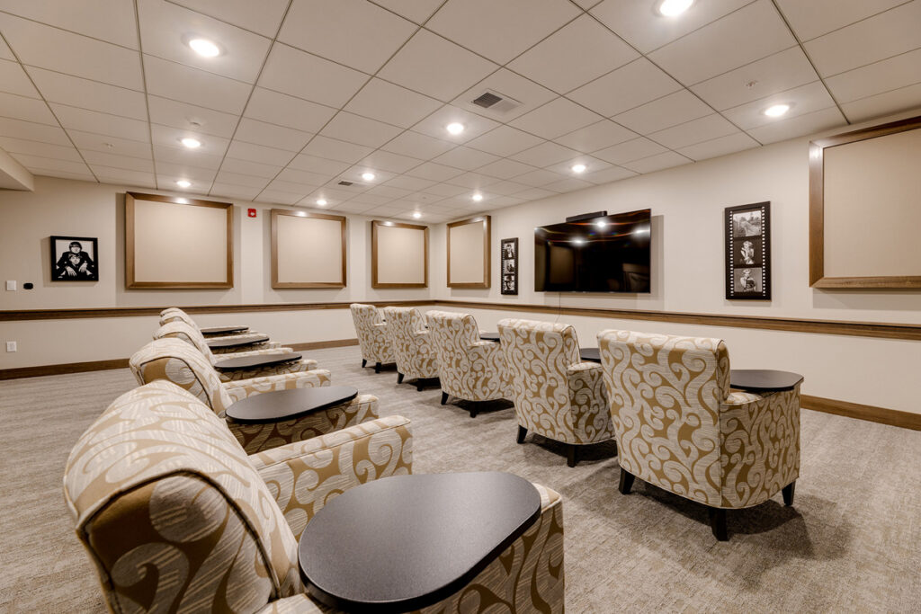Theater room at Meadowview of Johnston featuring comfortable seating and a large screen for movies, entertainment, and resident events.